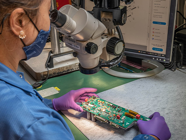 Receive a quality control process with Indianapolis PCB Manufacturing from DIVSYS image shows technician studying circuit board