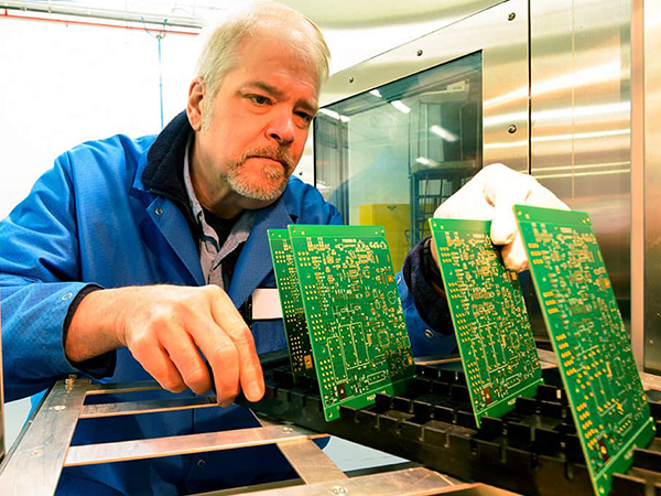 DIVSYS can include washing with its Indianapolis PCB Manufacturing services image shows technician studying circuit board materials