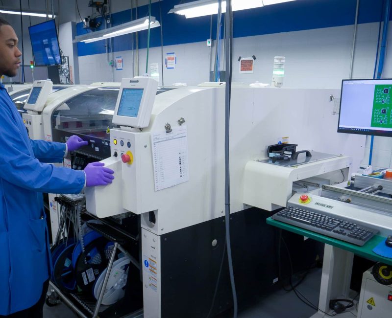 DIVSYS provides Indianapolis PCB Manufacturing solutions from prototype to product image shows technician studying board